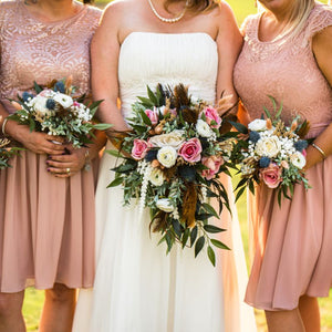 Unique wedding bouquets made with dusty rose roses, blue thistle, and brown feathers 